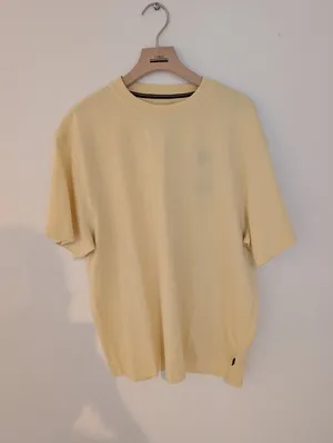 Mobilfoto af en gul t-shirt på bøjle
